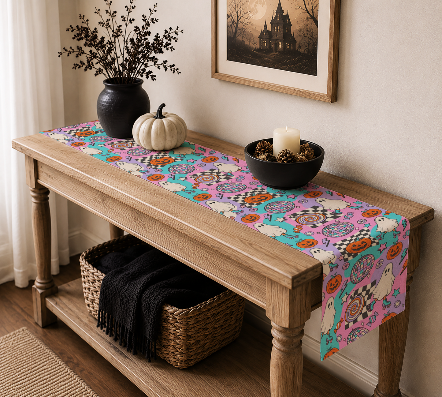 A colorful Halloween-themed table runner with cartoon ghosts, pumpkins, and spooky patterns draped over a wooden console table in a styled home interior.