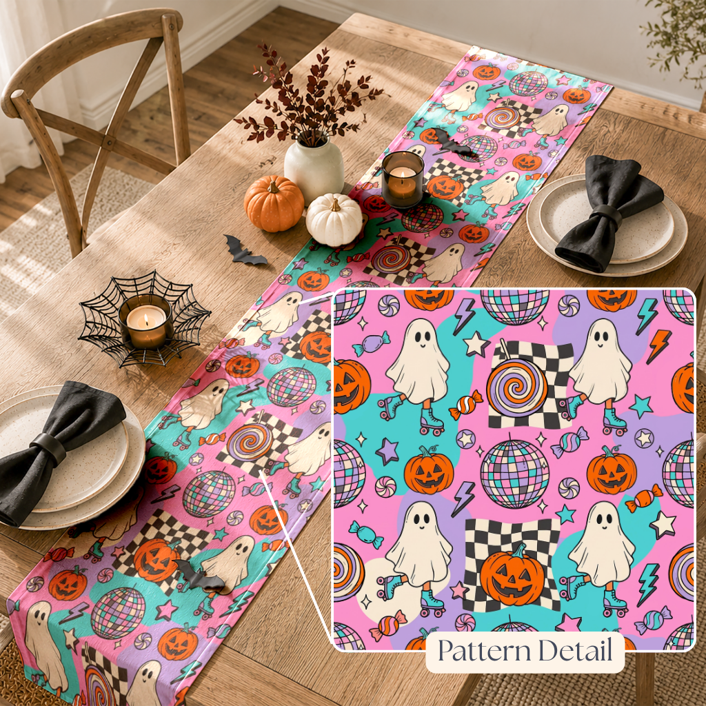 A Halloween-themed table runner displayed on a wooden dining table, with a matching inset detail box showing the pattern. The runner features a colorful print of ghosts, pumpkins, candy, stars, and disco balls on pink, purple, and teal backgrounds.